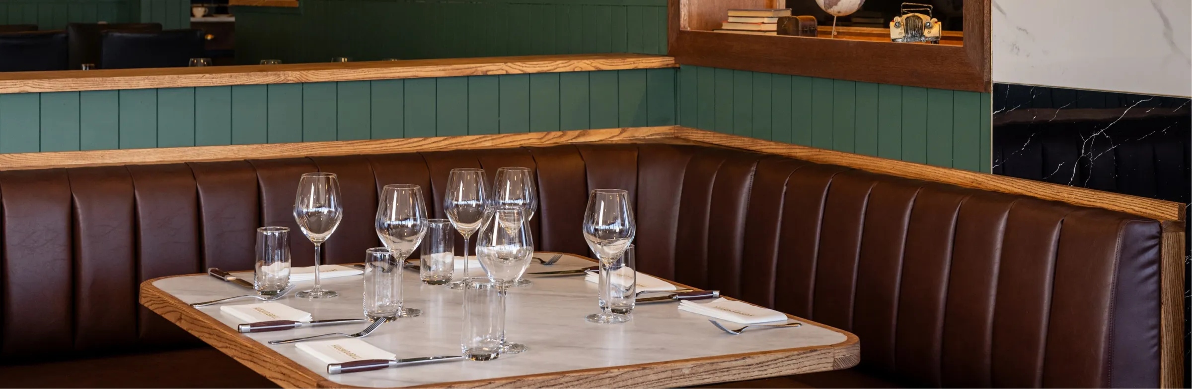 A leather banquette and a table set with white linen and glassware