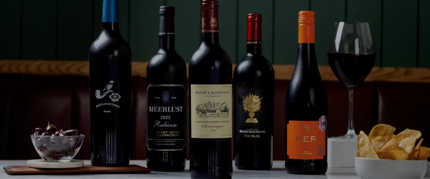 Red wines on a table in front of green panelling